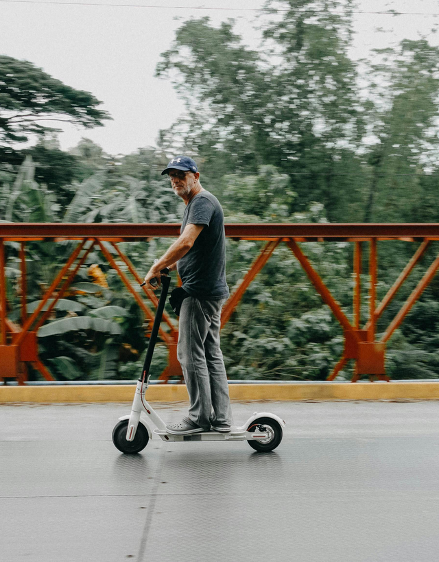 Homme en trottinette électrique sur un pont — Assurance Coverd contre la casse, l'oxydation et le vol
